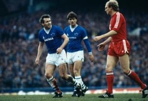 Everton’s Peter Reid, with his badly gashed leg bleeding through his sock, looks angrily towards Bayern Munich’s Dieter Hoeness as Everton captain Kevin Ratcliffe looks on.