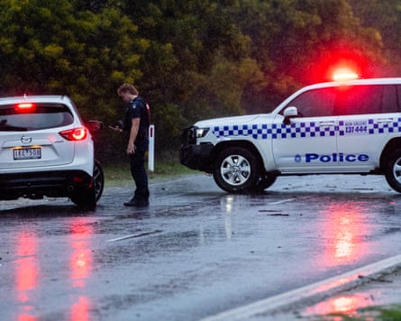 Police officers turn around traffic at a roadblock on Mt Buffalo Road in torrential rain, just west of Porepunkah.