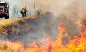 Bombeiros são vistos através do calor enquanto combatem o 'Apple Fire'