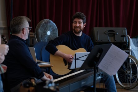 A man seated with a guitar.