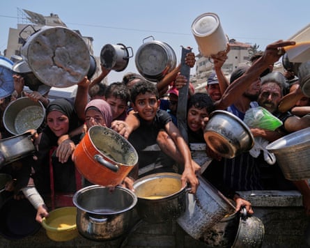 Palestinians struggle to get food at a community kitchen in Gaza City, northern Gaza Strip, 26 July.