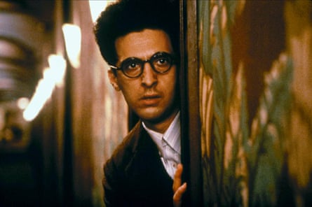 a man in glasses peers out from a door