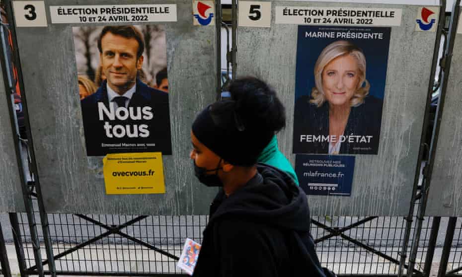 People walking past campaign posters of Emmanuel Macron and Marine le Pen in Paris.