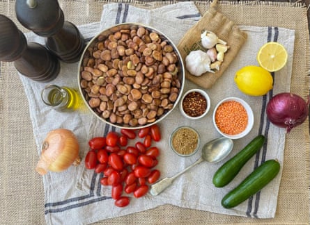 Dried broad beans, tomatoes, lentils, cucumbers and halves lemons on a linen cloth.