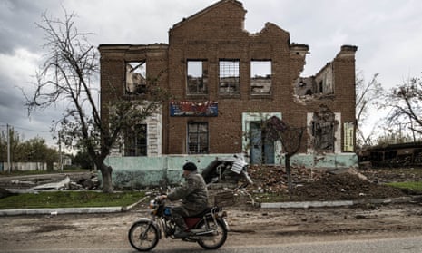 A man rides past a damaged building in the city of Lyman in the Donetsk region, Ukraine.