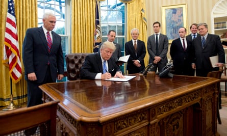 Trump signing the executive orders, surrounded by men.