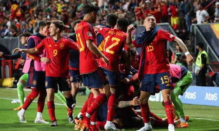 Joselu, sitting on the floor, is surrounded by his celebrating Spain teammates. 