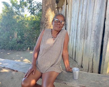 A woman sitting on a bench outside a wooden house.