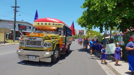 People dressed in blue walk beside a bus draped with flags supporting the team