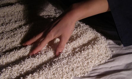 A hand making ridges in some rice spread out on a sheet. The rice will be used to make sake.