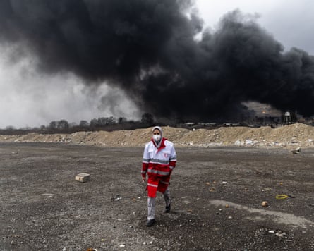 Iranian Red Crescent volunteer walks away from smoke rising from the Shahran oil depot in Tehran
