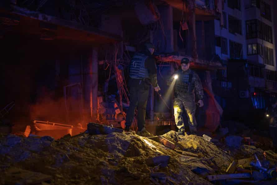 Police officers and army members inspect the debris following an explosion in Kyiv.