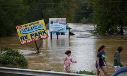 signs for a trailer park protrude from flood waters