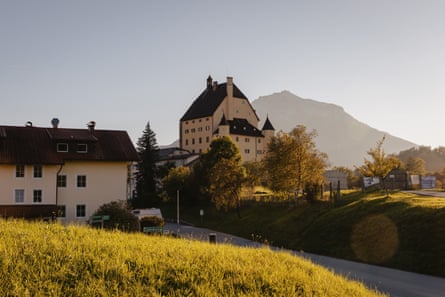 The cream coloured building is slightly elevated and behind it in shadow is a tall hill