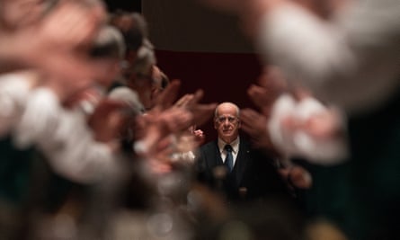 A man standing in the background with blurred hands clapping in the foreground