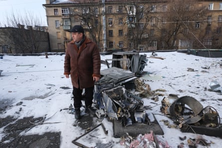 A man standing next to some mangled metal in a snowy courtyard