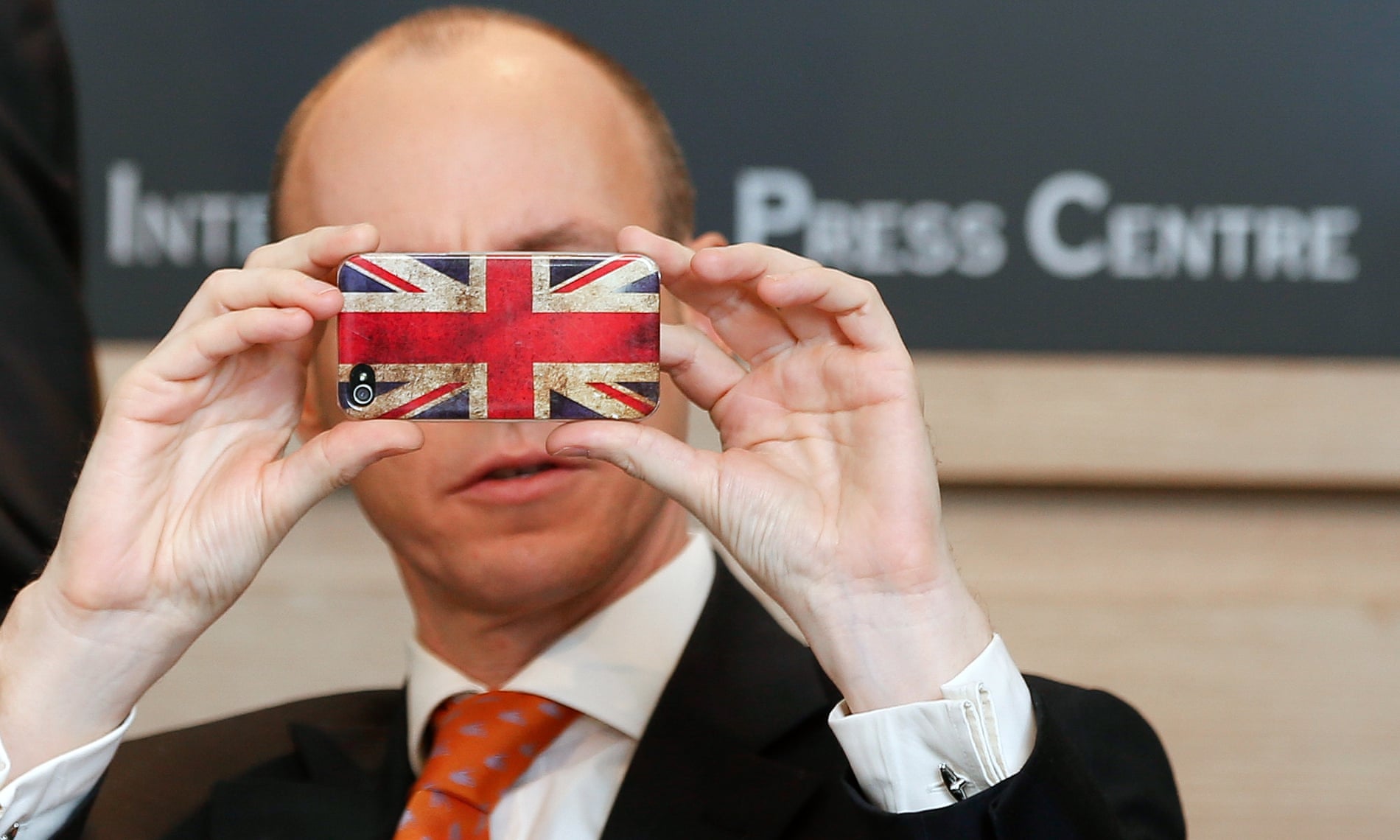 Daniel Hannan takes a picture with his smartphone during a press conference of the Alliance of European Conservatives and Reformists in Brussels