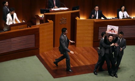 A pro-democracy politician is pulled away by security guards as he protests at a speech by Hong Kong’s chief executive, Carrie Lam, top left, this month.