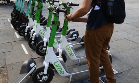 A man picks up a Lime electric scooter outside South Kensington Station in London.