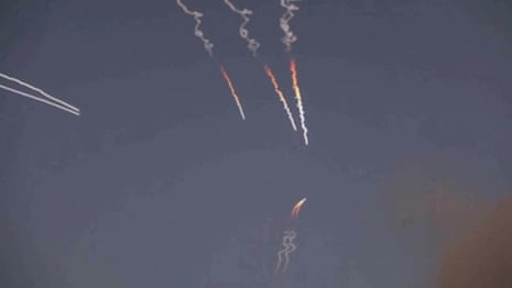 A still image from a video showing three or four missiles in the air.