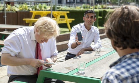 Rishi Sunak and Boris Johnson use their phones while sitting at a table outside
