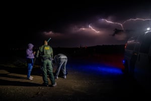 Border patrol officer and migrants in the dark