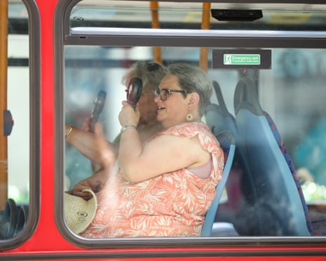 A woman uses an electric fan to cool down on a bus in London, England.