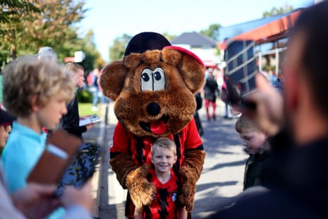 A young Bournemouth fan poses with the mascot Cherry Bear outside the stadium before the match.