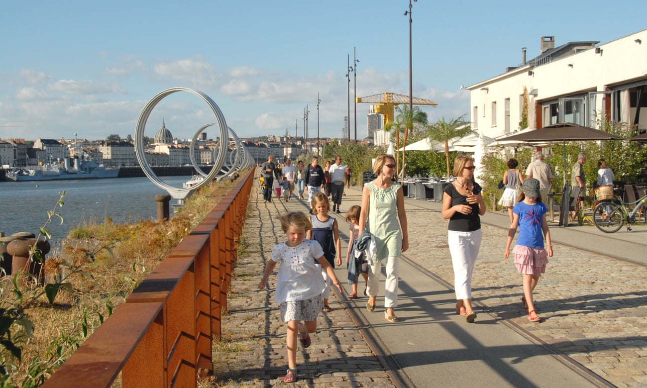 On a sunny day, a family walks along the Quai des Antilles on the Ile de Nantes, a revitalised port area on a Loire island in Nantes, France.