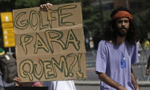 A protestor next a sign to reading ‘Golf for whom?’ during a protest on Copacabana beach against the Olympics