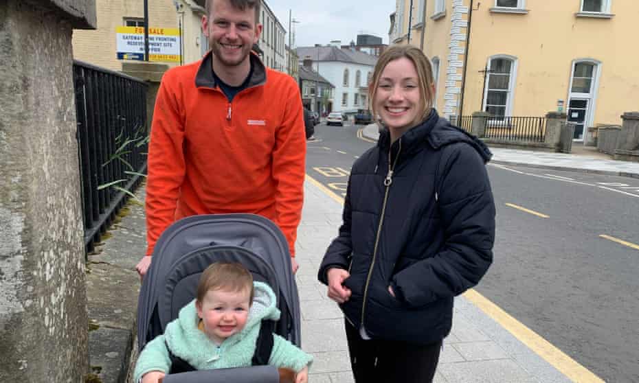 Mark and Grace Hoy smiling in street with their toddler.
