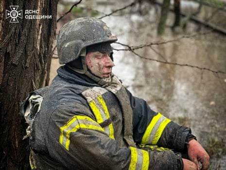 An injured rescuer sits under a tree at the site of a Russian missile strike in Odesa.