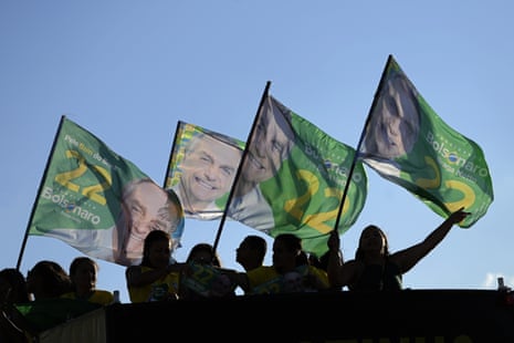 Supporters carry flags with the image of Jair Bolsonaro on them during a rally.