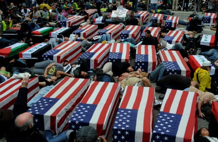 Protesters stage a die-in by laying in American flag coffins