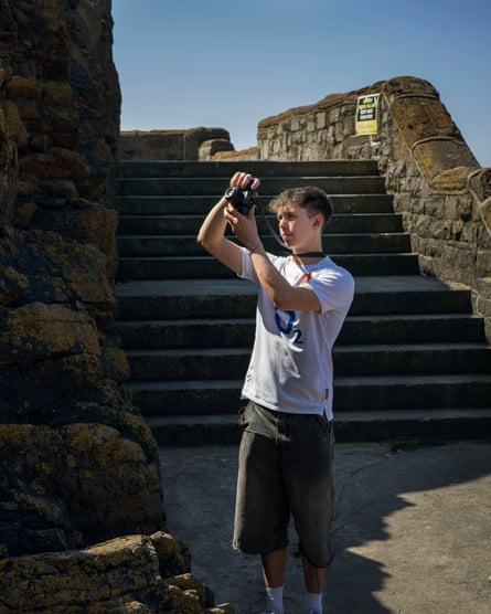 A man stands holding a camera in front of some steps