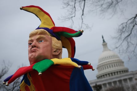 a person holds a satirical puppet of Trump as a jester