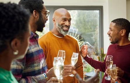 Cheerful group of relatives at family gatheringExtended family standing in living room at family gathering relaxing with drinks, talking and smiling together, bonding, celebration, happiness