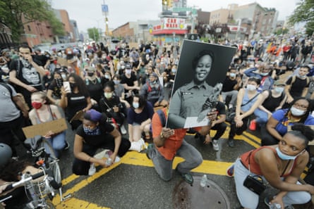 A man holds a photograph of Breonna Taylor on her birthday as he kneels with other protesters on Atlantic Avenue in Brooklyn.