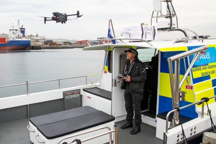 A man on a police boat flies a drone