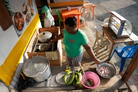 A woman seen at a cooker at a roadside stall with plantains and fish preparing a local dish