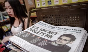 A woman walking past an edition of the South China Morning Post carrying the story of US intelligence whistleblower Edward Snowden (R) on its front page in Hong Kong.