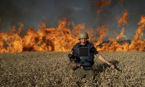 Photojournalist Evgeniy Maloletka runs from a blaze in a burning wheat field  in the Kharkiv region