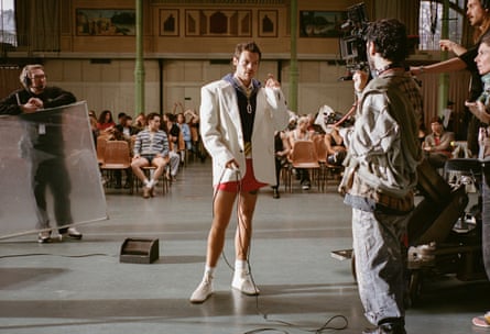 Harry Styles in a white jacket and short red shorts