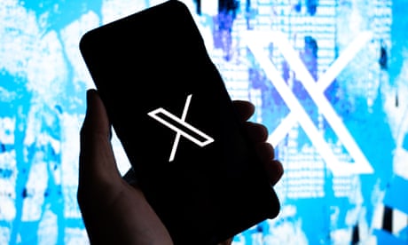 The X logo on a phone screen in front of a Twitter-branded graphic