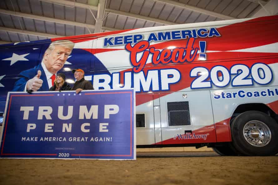 A couple poses for a photo in front of a Trump campaign bus at a rally in Alpharetta, Georgia, on 2 December 2020.