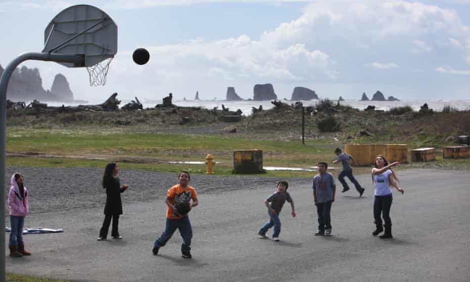 Students at the Quileute Tribal School play basketball playground as the Pacific Ocean waves crash just yards away in the Quileute community of La Push, Washington.