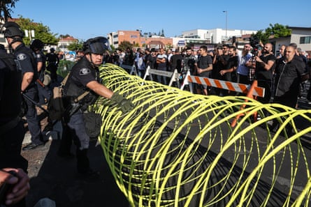 police behind bright-yellow circles of wire, with protesters on the other side