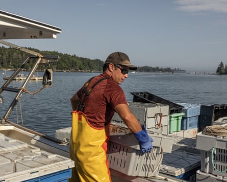 A man in oilskin dungarees hauling crates on a boat