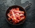 Streaky bacon pieces in a cast iron skillet.