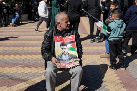A relative holds a picture of prominent Palestinian prisoner Zakaria Zubeidi as families wait for prisoners to be released from Israeli prisons, in the West Bank city of Ramallah.